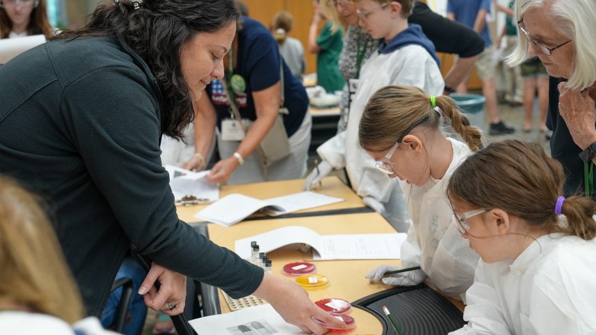 Children In Lab Coats And Safety Glasses Look At Culture Plates